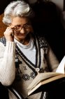 Ältere Frau liest mit Begeisterung am Fenster — Stockfoto