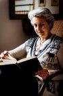 Пожилая женщина, читающая через окно с энтузиазмом — стоковое фото