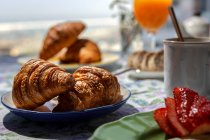 Desayuno completo en el brunch casero a la luz del sol con croissants, fresas, té o café y zumo de naranja - foto de stock