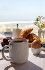 Домашний завтрак на завтрак в солнечном свете с приготовленными яйцами, черникой, бисквитом, круассанами, тостами, чаем, кофе и апельсиновым соком — стоковое фото