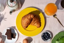 De cima vista superior de café da manhã completo caseiro sob luz solar com croissants, morangos, chá ou café e suco de laranja — Fotografia de Stock