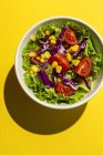 Fresh lettuce salad with Cherries tomatoes, red onion and corn, sunlight on pink background from above. Healthy food. Vegan food. — Stock Photo