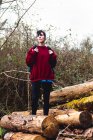 Frau in lässiger Kleidung und Turnschuhen mit Rucksack, während sie tagsüber in Spanien auf Holzstämmen steht und am Hang inmitten von Grün im Wald ruht — Stockfoto