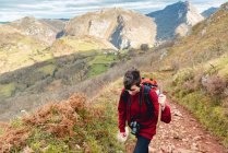 Подорожуючи по гірській дорозі під хмарним небом Іспанії, екскурсанти з рюкзаком і палицею — стокове фото