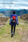 Rückansicht eines Touristen mit Rucksack und Stock beim Wandern unter bewölktem Himmel in Spanien, der wegschaut und die malerische Landschaft bewundert — Stockfoto