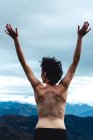 Rückenansicht einer oben ohne stehenden Frau mit erhobenen Armen, die Freiheit und Wildheit genießt, während sie die idyllische Landschaft eines nebligen Berges bei bewölktem Wetter in Spanien betrachtet — Stockfoto