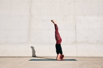 Вид збоку невідомого босоніжого спортсмена в активному одязі, що стоїть догори ногами в положенні Сірасана з піднятими ногами — стокове фото