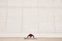 Неузнаваемая спортсменка в спортивной одежде делает широконогую позу для йоги на спортивном коврике, тренируясь в одиночку — стоковое фото
