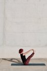 Da sopra vista laterale di irriconoscibile donna scalza con capelli ricci rossi in abbigliamento sportivo in piedi a testa in giù in posa barca — Foto stock