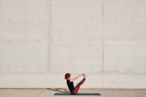 From above side view of unrecognizable barefooted woman with red curly hair in sportswear standing upside down in boat pose — Stock Photo