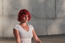 Жінка з рудим волоссям і татуюванням у білій сорочці і бургундських штанях сидячи в падмасані з Джан Мудра і медитуючи з закритими очима. — стокове фото