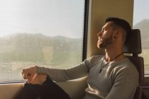 Pensativo joven pasajero masculino sentado en el vagón del metro - foto de stock
