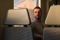Pensativo joven pasajero masculino escuchando música en el vagón del metro - foto de stock