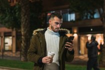Серьезный молодой человек, использующий смартфон на улице — стоковое фото