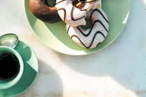 Склад ароматного гарячого напою та смачних пончиків на столі — стокове фото