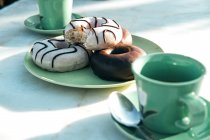 Склад ароматного гарячого напою та смачних пончиків на столі — стокове фото