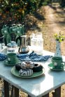 Alto angolo di gustose ciambelle con glassa sul piatto e tazze di bevanda calda accanto set da tavola e moka pot — Foto stock