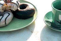 Composição de bebida quente aromática e saborosos donuts na mesa — Fotografia de Stock