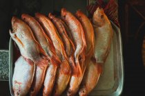 Vista superior de peixes limpos crus em linha na bandeja na cozinha rústica — Fotografia de Stock