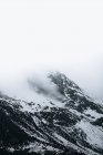 Paisagem fria severa do inverno com picos nevados da montanha com nevoeiro e tempestade de neve quebrando por toda parte — Fotografia de Stock