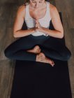 Calmo relaxado fêmea com os olhos fechados e namaste sentado na posição baddha konasana no tapete esportivo e concentrando-se enquanto pratica ioga no estúdio moderno escuro — Fotografia de Stock