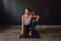 High angle of confident barefooted woman in sportswear stretching body in eka pada rajakapotasana two position on mat and looking away while training in spacious contemporary workout room — Stock Photo