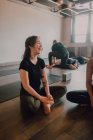 Hohe Blickwinkel junger, unterschiedlicher Frauen und Männer in Sportbekleidung, die in Lotus-Pose sitzen und interessante Diskussionen führen, während sie sich nach dem Gruppentraining im modernen Yoga-Studio ausruhen — Stockfoto
