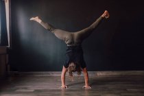 Back view of faceless barefooted man in sportswear standing upside down in downward facing dog pose while training in contemporary gym — Stock Photo