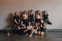 Selbstbewusste schlanke Sportler in Sportbekleidung, die vor schwarzer Wand eines dunklen modernen Studios eine andere Yogaposition ausführen — Stockfoto