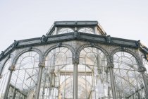 Castillo antiguo geométrico con ventanas de cristal que reflejan árboles, Palacio de Cristal, Parque del Retiro, Madrid, España - foto de stock