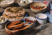 Piatti serviti di formaggio, hummus e carne a scatti con focaccia sul tavolo grigio — Foto stock
