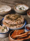Servierte Gerichte aus Käse, Hummus und Ruckfleisch mit Fladenbrot auf grauem Tisch — Stockfoto