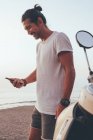 Feliz homem ativo usando telefone à beira-mar — Fotografia de Stock