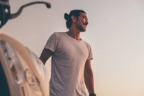 Positiver Mann mit Motorrad steht am Meer — Stockfoto