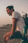 Щасливий чоловік з мотоциклом насолоджується заходом сонця на пляжі — стокове фото