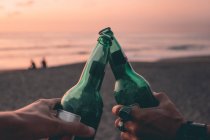 Обрізане зображення Друзів тости з пивом на пляжі заходу сонця — стокове фото