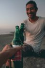 Amigos brindam com cerveja na praia do pôr do sol — Fotografia de Stock