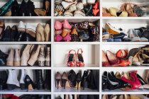 Современный белый шкаф и квадратные полки с женскими красочными дорогими туфлями на высоких каблуках и кроссовками — стоковое фото