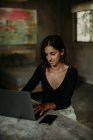 Sério mulher focada digitando no laptop enquanto sentado na mesa cozinha moderna bancada de mármore — Fotografia de Stock
