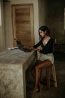 Серьезное внимание женщина печатает на ноутбуке, сидя за столом на кухне современного мраморного столешницы — стоковое фото