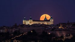 Maravilloso paisaje de palacio antiguo iluminado construido sobre la ciudad en colorida noche con luna roja llena en Toledo - foto de stock