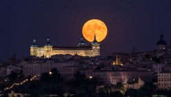 Maravilhoso cenário de palácio antigo iluminado construído sobre a cidade em noite colorida com lua vermelha cheia em Toledo — Fotografia de Stock