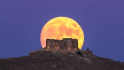 From below picturesque scenery of abandoned aged fortress on top of mountain illuminated by full Moon at night in Toledo — Stock Photo