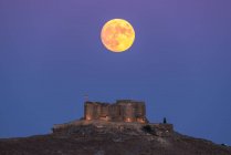 From below picturesque scenery of abandoned aged fortress on top of mountain illuminated by full Moon at night in Toledo — Stock Photo