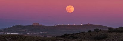 Dal basso pittoresco scenario della fortezza abbandonata sulla cima della montagna illuminata dalla luna piena di notte a Toledo — Foto stock