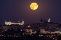 Maravilhoso cenário de palácio antigo iluminado construído sobre a cidade em noite colorida com lua vermelha cheia em Toledo — Fotografia de Stock