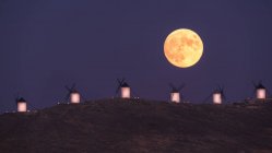 Paysage étonnant de pleine lune majestueuse sur la vallée avec des moulins à vent au coucher du soleil — Photo de stock