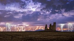 Incredibile scenario di tempesta di fulmini sul cielo nuvoloso colorato sopra vecchio castello in rovina di notte — Foto stock