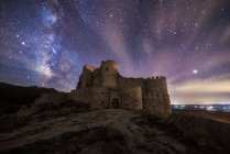 Удивительный пейзаж заброшенного древнего дворца на горе под красочным звездным небом ночью — стоковое фото