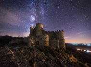 Amazing scenery of abandoned ancient palace on mountain under colorful starry sky at night — Stock Photo